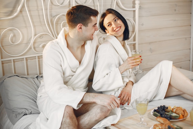 Linda pareja en el dormitorio con albornoces desayunando.