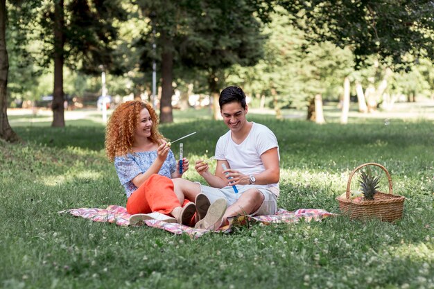 Linda pareja jugando con burbujas en picnic