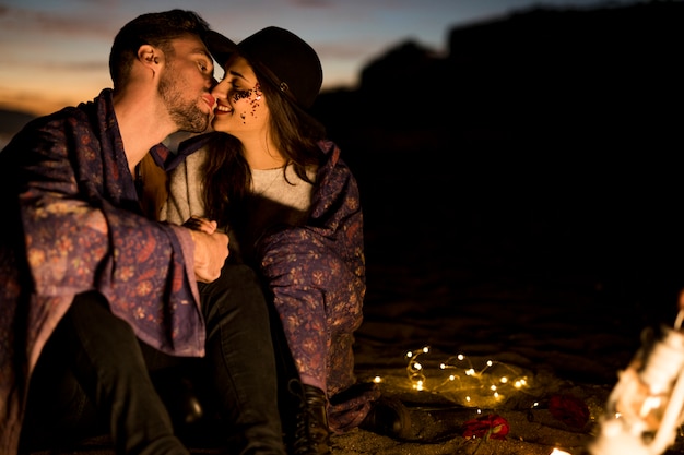 Foto gratuita linda pareja en manta besándose en la orilla del mar