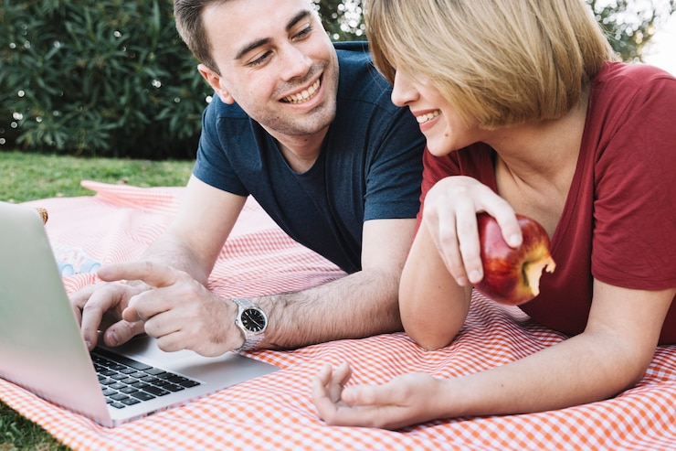 Foto gratuito linda pareja navegando portátil en picnic