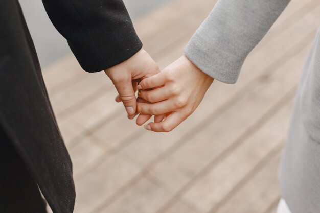 Linda pareja en un parque. Dama con un abrigo gris. Gente en el muelle.