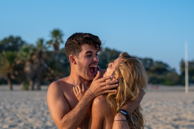 Linda pareja en la playa abrazándose y riendo