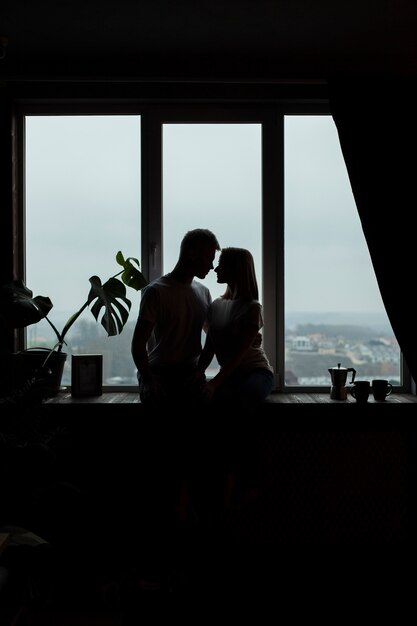 Linda pareja posando junto a la ventana