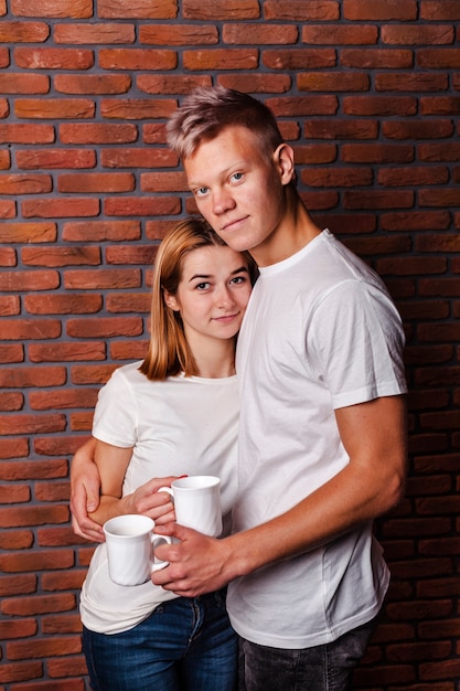 Linda pareja posando con sus tazas de café