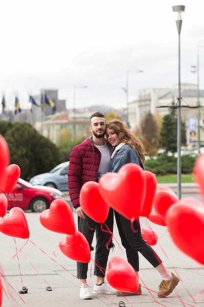 Linda pareja rodeada de globos de corazón