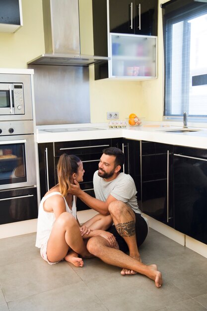 Linda pareja sentada en el piso en la cocina