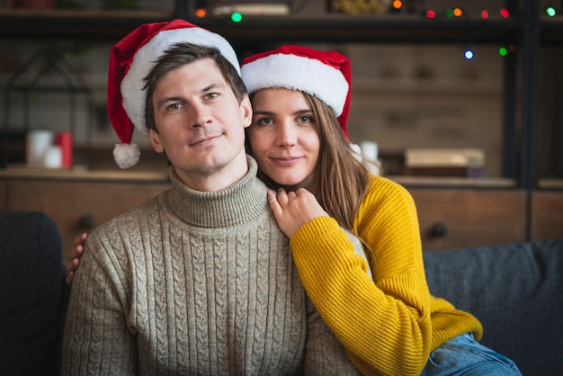 Foto gratuita linda pareja con sombreros y suéteres de santa