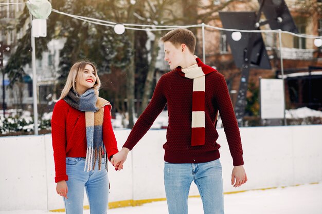 Linda pareja en un suéter rojo divirtiéndose en una arena de hielo