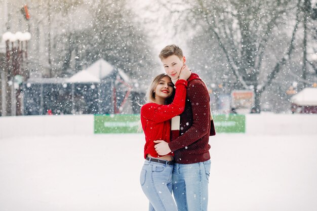 Linda pareja en un suéter rojo divirtiéndose en una arena de hielo