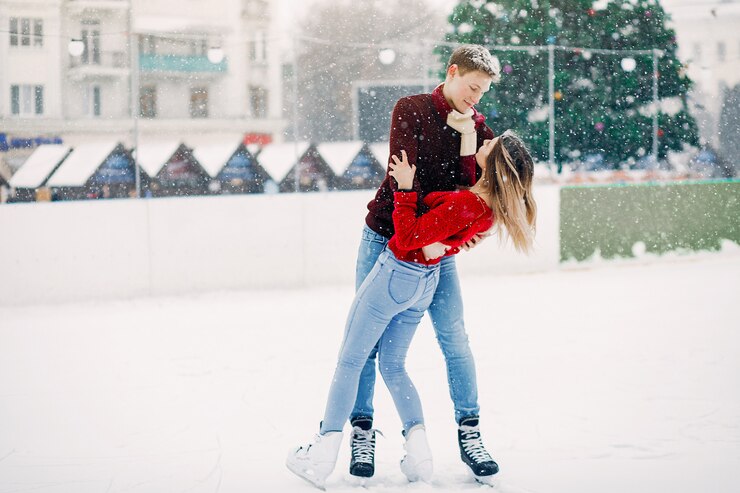Foto gratuito linda pareja en un suéter rojo divirtiéndose en una arena de hielo