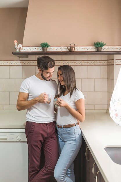 Linda pareja con tazas en la elegante cocina