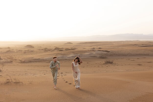 Linda pareja de tiro largo caminando en el desierto