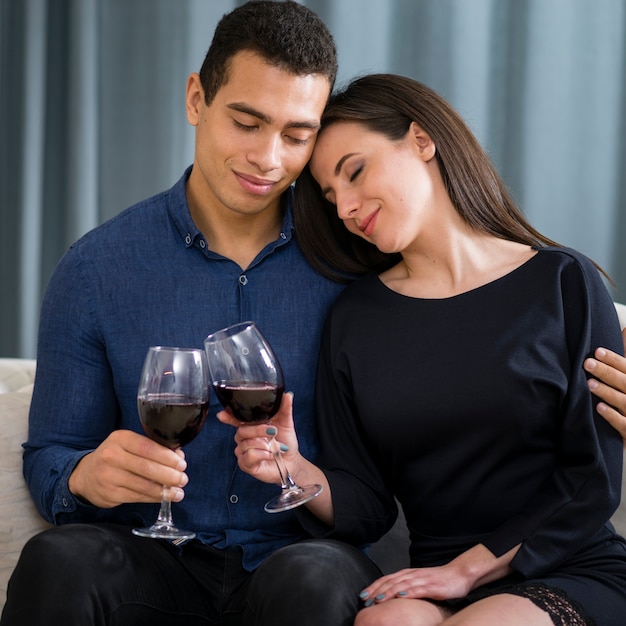 Foto gratuita linda pareja tomando una copa de vino mientras está sentado en el sofá