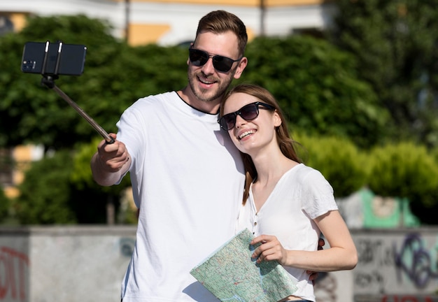 Linda pareja de turistas sosteniendo el mapa y tomando selfie