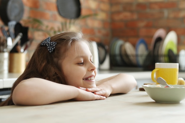 Linda y sonriente niña en la cocina, desayuno