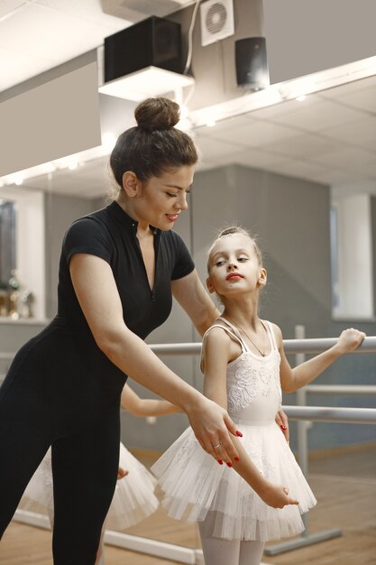 Lindas bailarinas en traje de ballet rosa. Niños con zapatillas de punta bailan en la habitación. Niño en clase de baile con maestra.