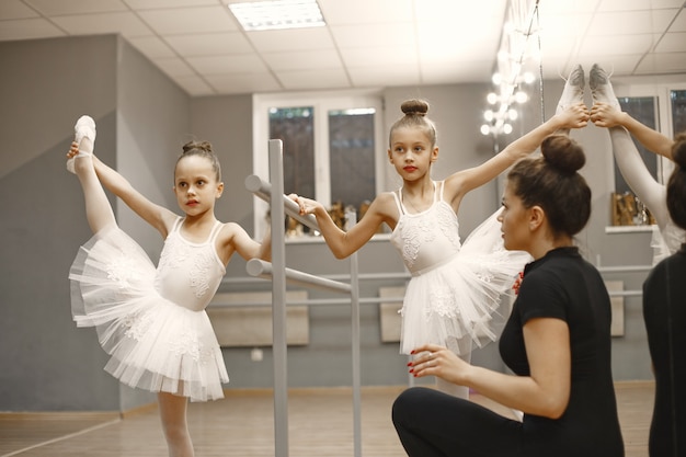 Lindas bailarinas en traje de ballet rosa. Niños con zapatillas de punta bailan en la habitación. Niño en clase de baile con maestra.