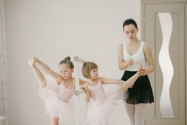 Lindas bailarinas en traje de ballet rosa. Niños con zapatillas de punta bailan en la habitación. Niño en clase de baile con teatcher.