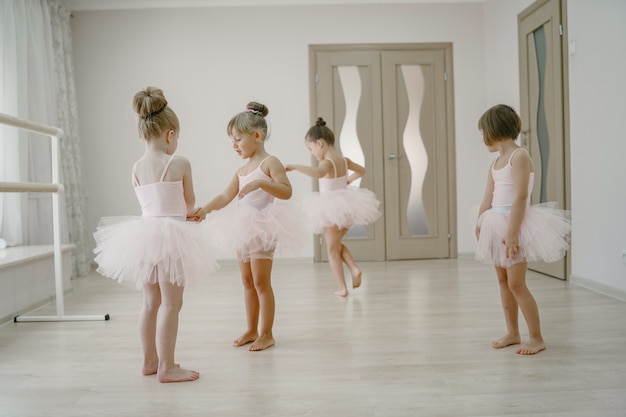 Foto gratuita lindas bailarinas en traje de ballet rosa. los niños con zapatos de punta bailan en la habitación.