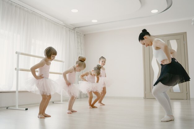 Lindas bailarinas en traje de ballet rosa. Los niños con zapatos de punta bailan en la habitación.
