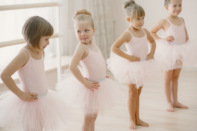 Lindas bailarinas en traje de ballet rosa. Los niños con zapatos de punta bailan en la habitación.