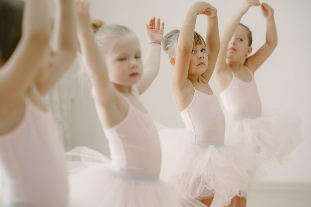 Lindas bailarinas en traje de ballet rosa. Los niños con zapatos de punta bailan en la habitación.