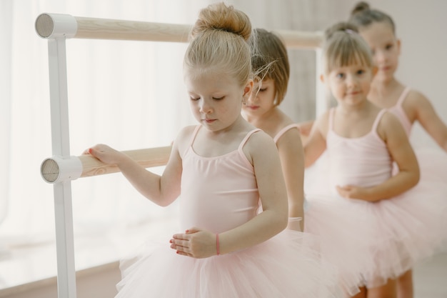 Foto gratuita lindas bailarinas en traje de ballet rosa. los niños con zapatos de punta bailan en la habitación.