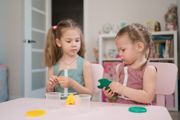 Lindas niñas moldeadas de plastilina en mesa rosa