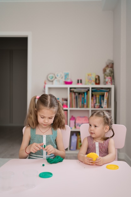 Lindas niñas moldeadas de plastilina en mesa rosa