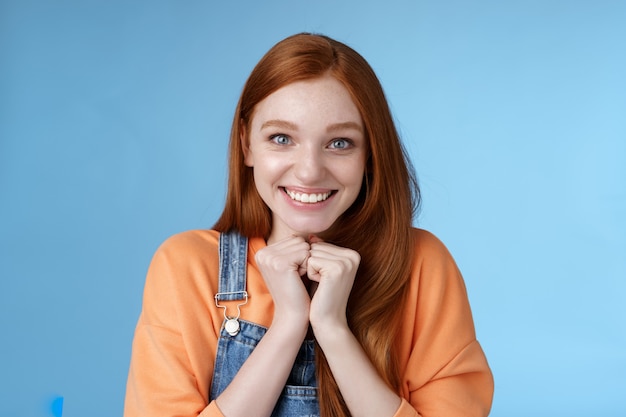 Lindo atractivo emocionado sonriendo feliz pelirroja chica ojos azules pecas reciben increíble oportunidad de estudiar en el extranjero sonriendo regocijo mirada muy agradecida cámara sorprendida agradecida, fondo azul.