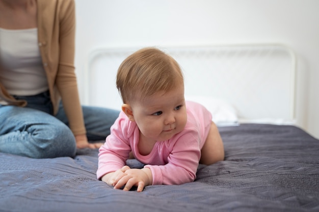 Lindo bebé aprendiendo a gatear en la cama en ángulo alto