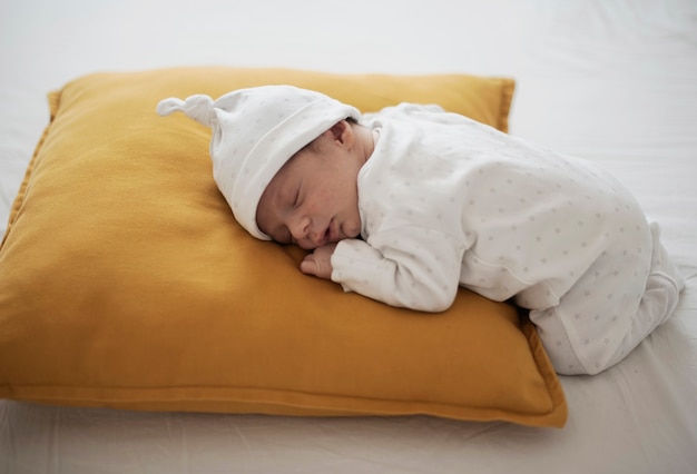 Lindo bebé durmiendo sobre una almohada amarilla