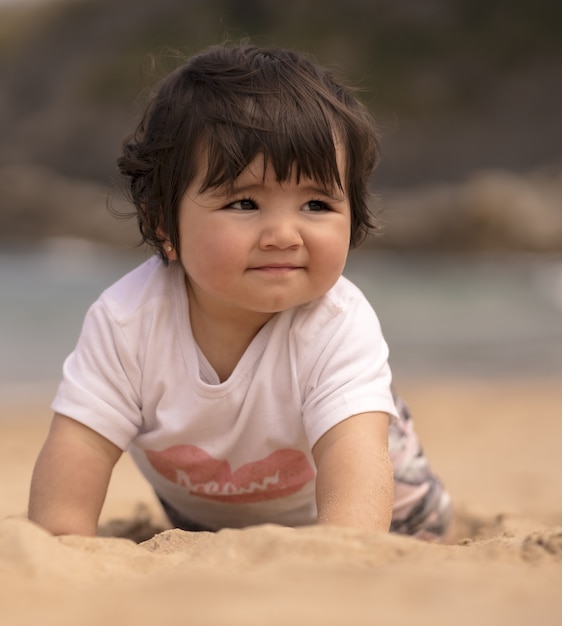 Lindo bebé español en una playa de arena