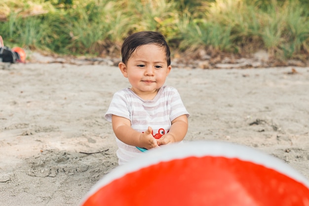 Lindo bebé jugando con la pelota en la playa