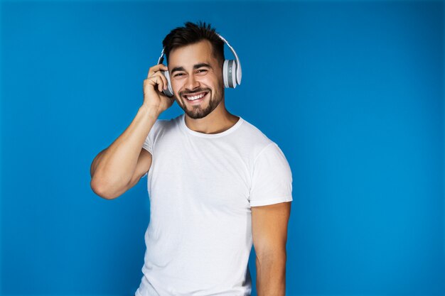 Lindo hombre europeo sonríe y escucha algo en los auriculares