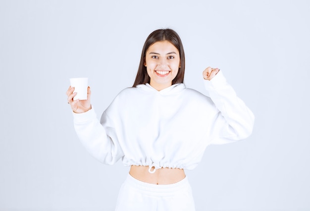 lindo modelo de niña sosteniendo un vaso de plástico.