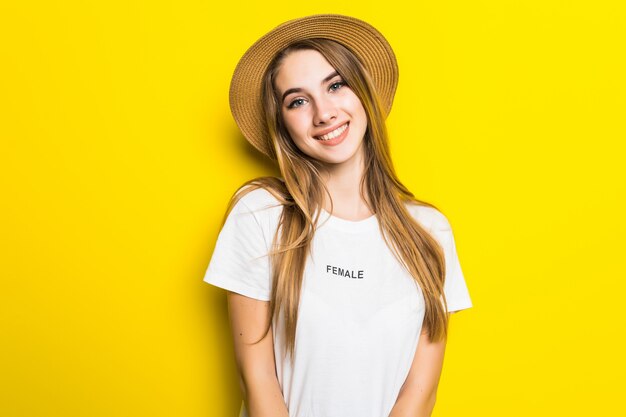 Lindo modelo sonriente en camiseta blanca y sombrero entre fondo naranja con cara divertida