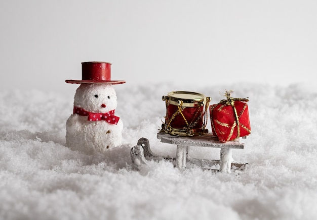 Lindo muñeco de nieve, trineo y coloridas cajas de regalo en la nieve.