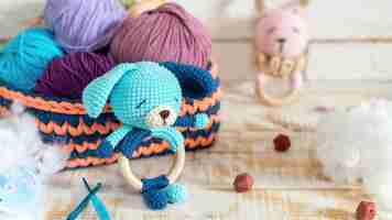 Foto gratuita lindo muñeco de peluche tejido y ovillos multicolores en el sofá tejido con felpa alrededor