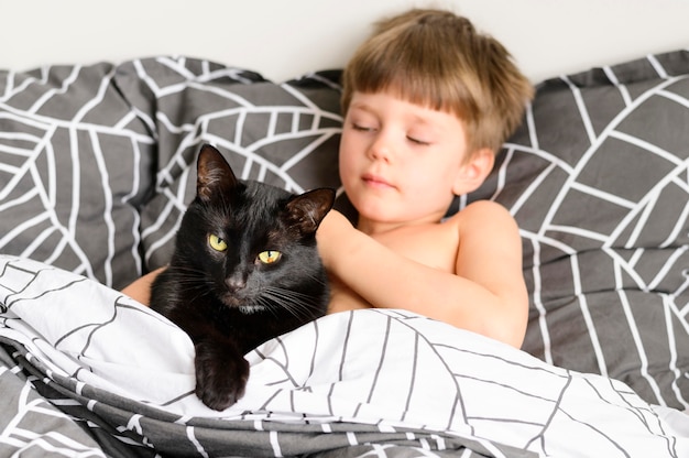 Lindo niño acariciando a su gato en casa