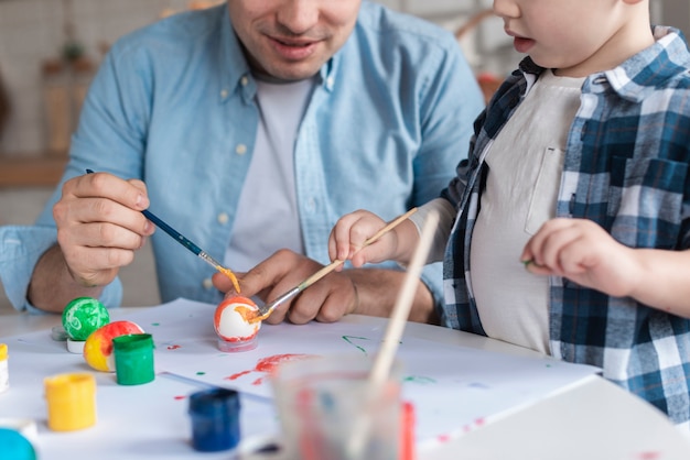 Lindo niño aprendiendo a pintar huevos de pascua