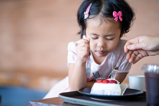 Lindo niño asiático come un pastel