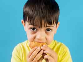 Foto gratuita lindo niño comiendo un croissant