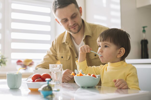 Lindo niño pequeño y su padre comiendo cereales