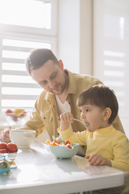 Lindo niño pequeño y su padre comiendo