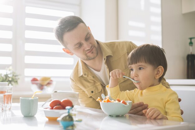 Lindo niño pequeño y su padre sentado vista lateral