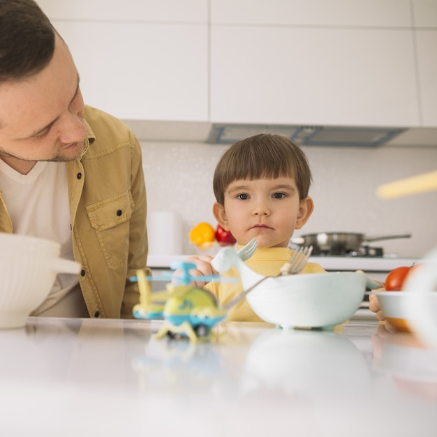 Foto gratuita lindo niño pequeño y su papá en la cocina