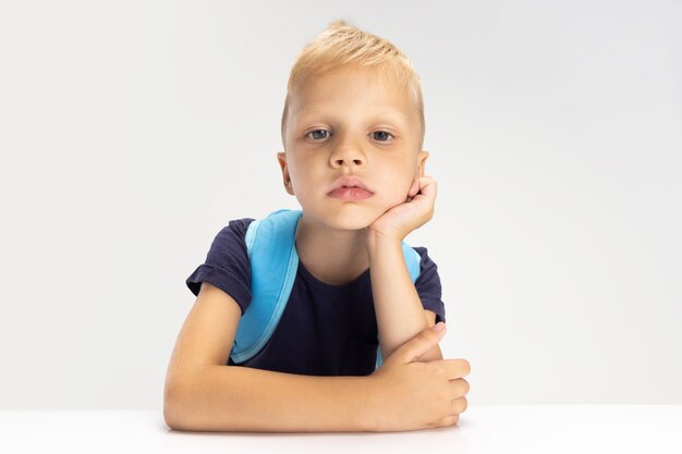 Un lindo niño preescolar aislado en la pared blanca del estudio