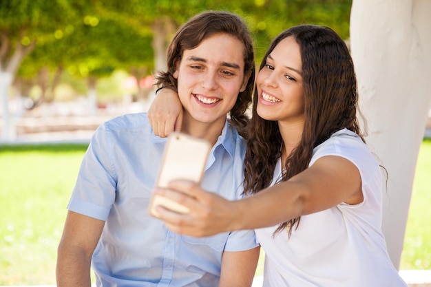 Lindo par de estudiantes universitarios tomando un selfie en la escuela con un teléfono