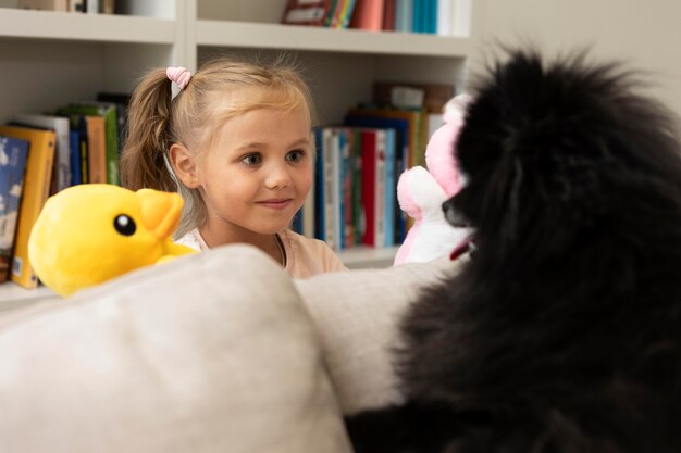 Foto gratuita lindo perro mirando a una niña con una marioneta de pato